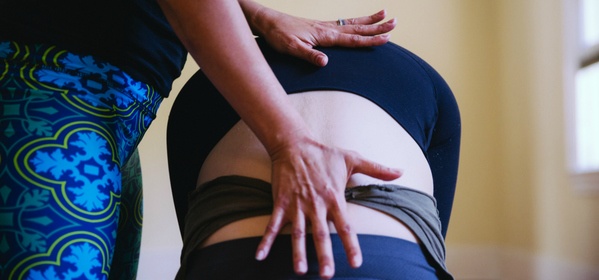 Photo of yoga teacher adjusting student